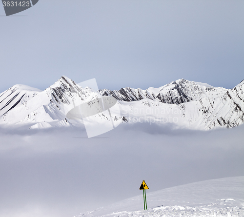 Image of Mountains in mist and warning sing on ski slope