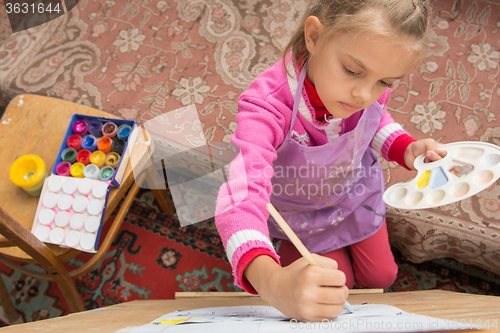 Image of Top view risuyuschuyu five-year girl on an easel in the studio of the artist
