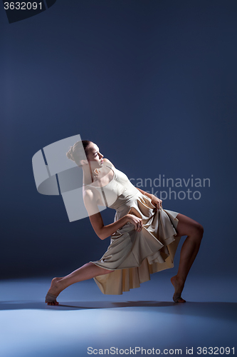 Image of Young beautiful dancer in beige dress dancing on gray background