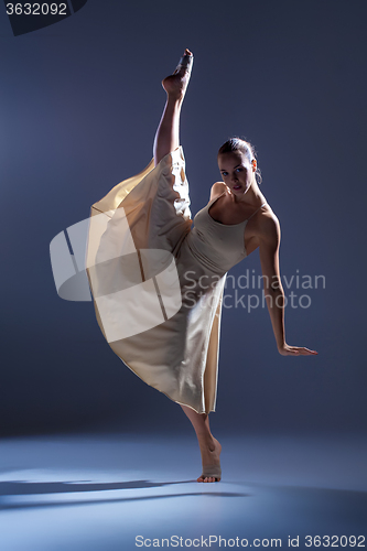 Image of Young beautiful dancer in beige dress dancing on gray background