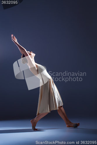 Image of Young beautiful dancer in beige dress dancing on gray background