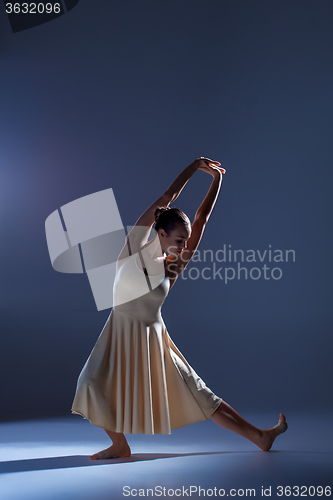 Image of Young beautiful dancer in beige dress dancing on gray background