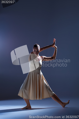 Image of Young beautiful dancer in beige dress dancing on gray background