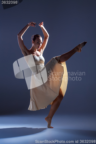Image of Young beautiful dancer in beige dress dancing on gray background