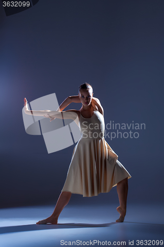 Image of Young beautiful dancer in beige dress dancing on gray background