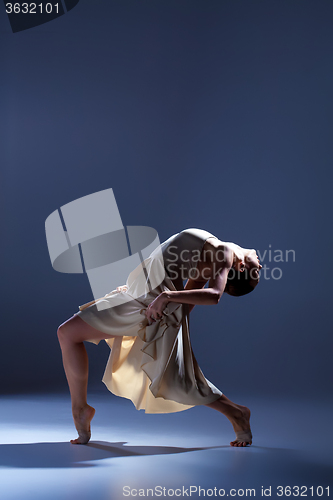 Image of Young beautiful dancer in beige dress dancing on gray background