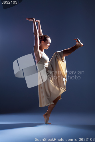 Image of Young beautiful dancer in beige dress dancing on gray background