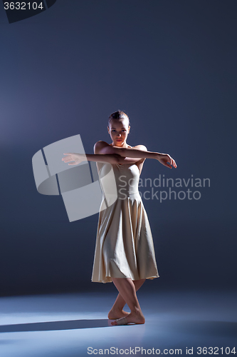 Image of Young beautiful dancer in beige dress dancing on gray background