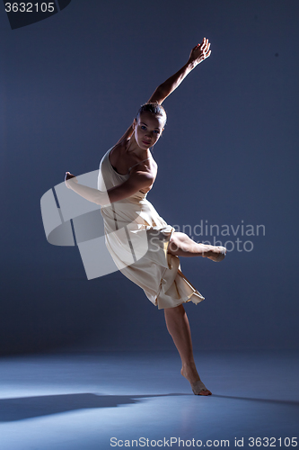 Image of Young beautiful dancer in beige dress dancing on gray background