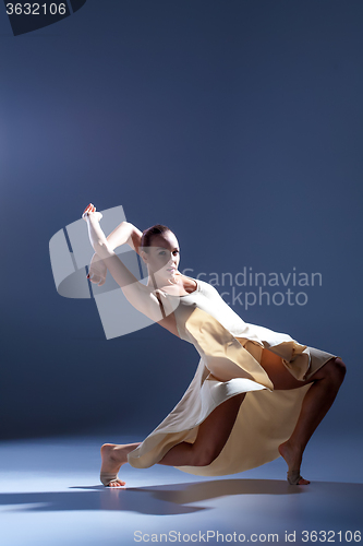 Image of Young beautiful dancer in beige dress dancing on gray background