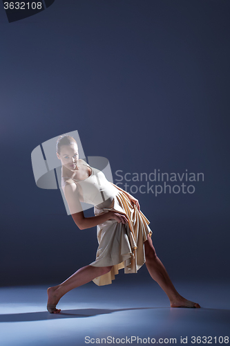 Image of Young beautiful dancer in beige dress dancing on gray background