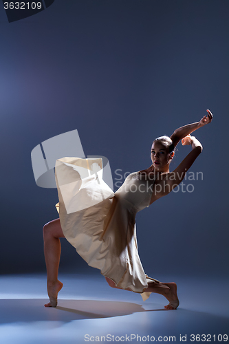 Image of Young beautiful dancer in beige dress dancing on gray background