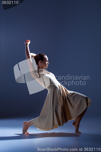 Image of Young beautiful dancer in beige dress dancing on gray background