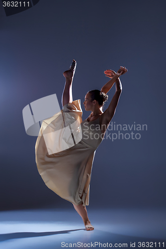 Image of Young beautiful dancer in beige dress dancing on gray background