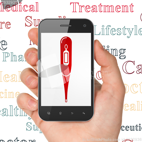 Image of Medicine concept: Hand Holding Smartphone with Thermometer on display