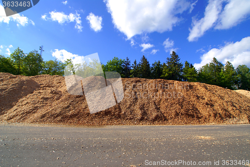 Image of storage of wooden bio fuel against blue sky