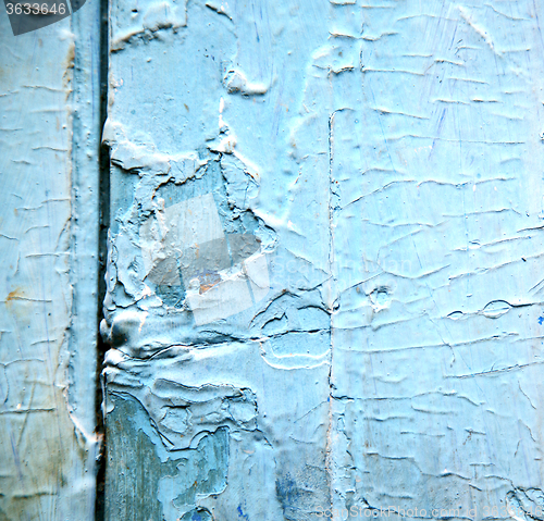 Image of dirty stripped paint in the blue wood door and rusty nail