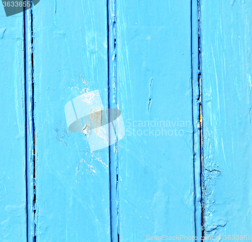 Image of stripped paint in the blue wood door and rusty nail