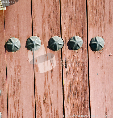 Image of nail dirty stripped paint in the brown wood door and rusty yello