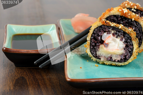 Image of Black sushi rolls served on turquoise plate