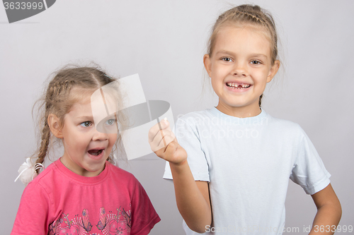 Image of Four-year girl with surprise stares at the lost tooth in his hand a six-year girl