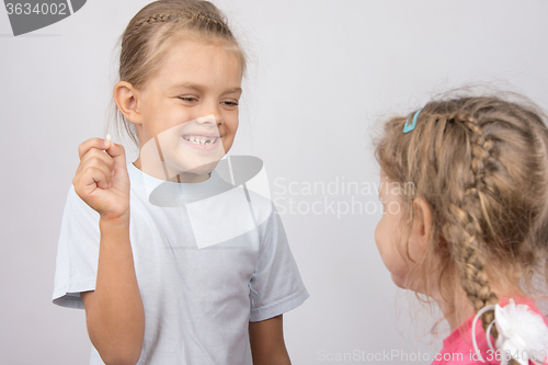 Image of Girl shows her the other girl had fallen front baby tooth