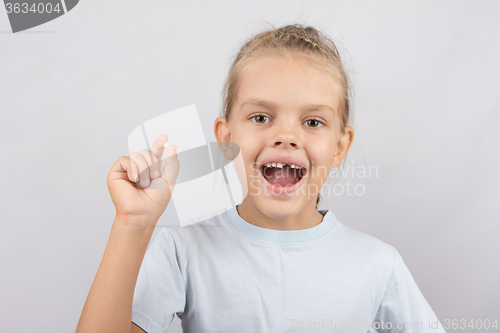 Image of Girl holds the tooth in his hand and his mouth open showing a hole between the teeth