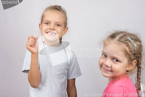 Image of Girl holding a fallen front tooth, standing next to another girl