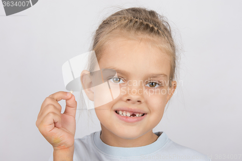 Image of Portrait of a girl with a fallen tooth in his hand