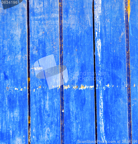 Image of dirty stripped paint in the blue wood door and rusty nail