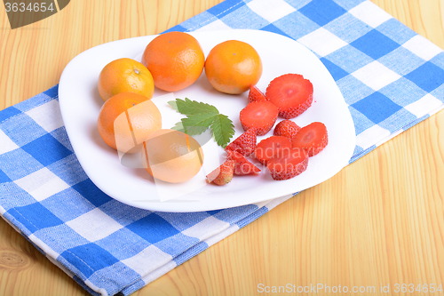 Image of A slice of red strawberry on white plate with mandarin and strawberry slices