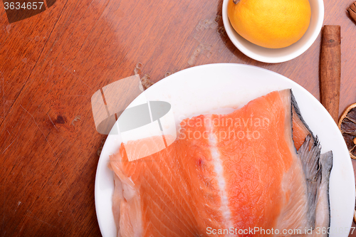 Image of Raw salmon fish steaks with fresh herbs on white plate