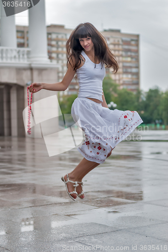 Image of Jumping smiling girl in rain city background