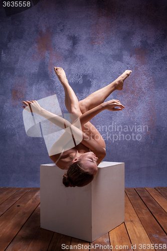 Image of Young beautiful dancer in beige swimwear posing on white cube