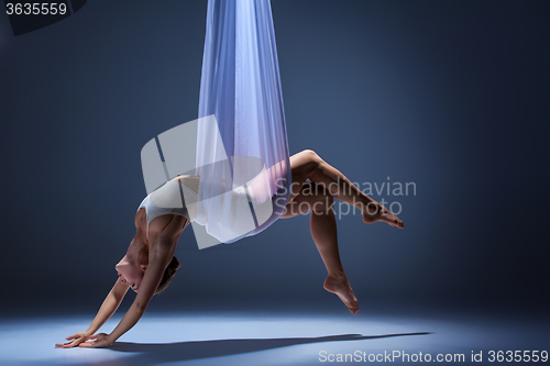 Image of Young beautiful dancer in beige dress posing on gray background