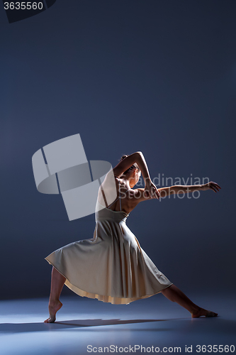 Image of Young beautiful dancer in beige dress dancing on gray background