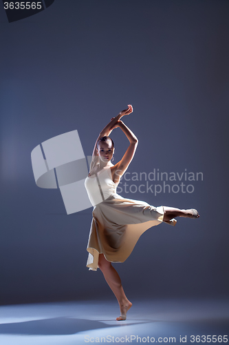 Image of Young beautiful dancer in beige dress dancing on gray background
