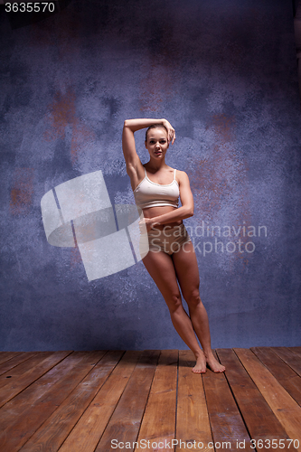 Image of Young beautiful dancer in beige swimwear dancing on lilac background