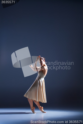 Image of Young beautiful dancer in beige dress dancing on gray background