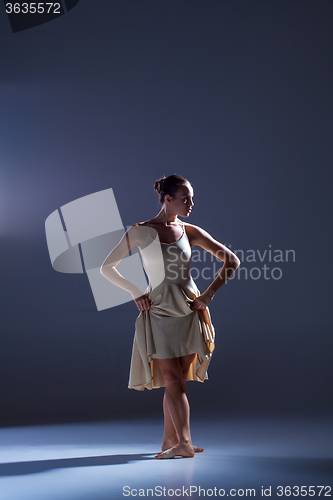 Image of Young beautiful dancer in beige dress dancing on gray background