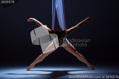 Image of Young beautiful dancer in beige dress posing on gray background