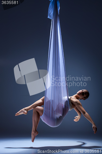 Image of Young beautiful dancer in beige dress posing on gray background