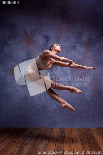 Image of Young beautiful dancer in beige swimwear dancing on lilac background