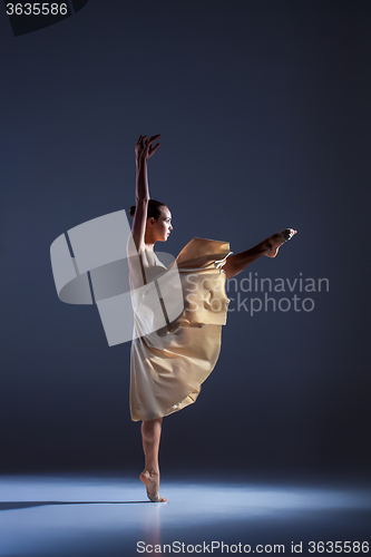 Image of Young beautiful dancer in beige dress dancing on gray background