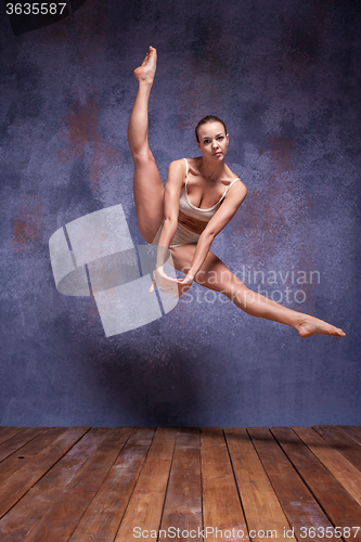 Image of Young beautiful dancer in beige swimwear dancing on lilac background