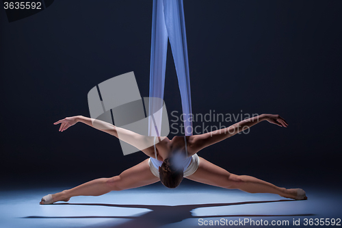 Image of Young beautiful dancer in beige dress posing on gray background