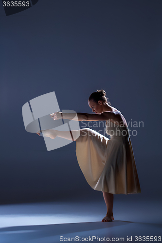 Image of Young beautiful dancer in beige dress dancing on gray background
