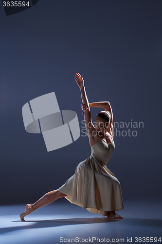 Image of Young beautiful dancer in beige dress dancing on gray background