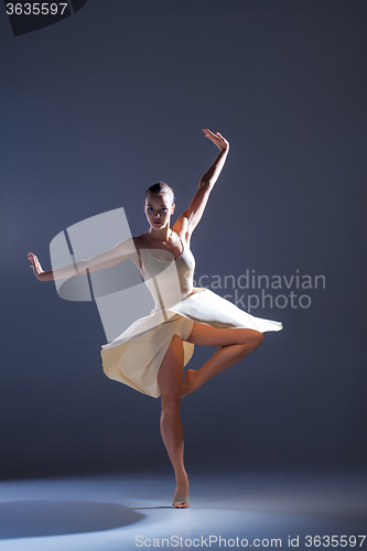 Image of Young beautiful dancer in beige dress dancing on gray background