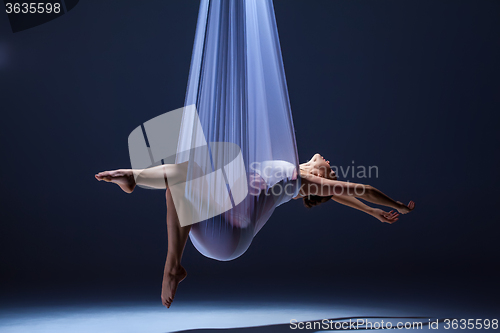 Image of Young beautiful dancer in beige dress posing on gray background